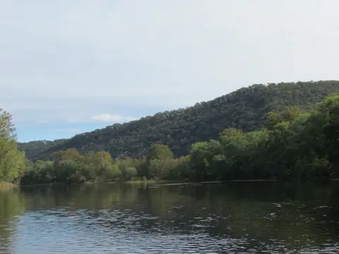 Calm river water below a green mountain