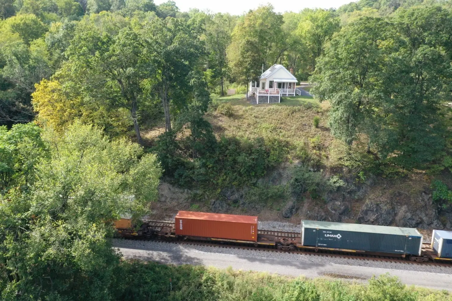 A container freight train passing below the house on its ridge