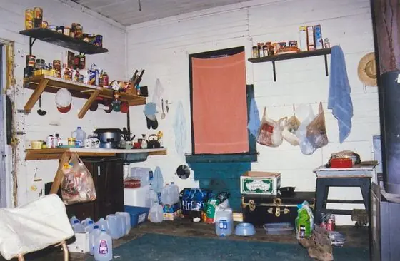 Inside the schoolhouse: shelves of food, water jugs and a wood stove in the one room