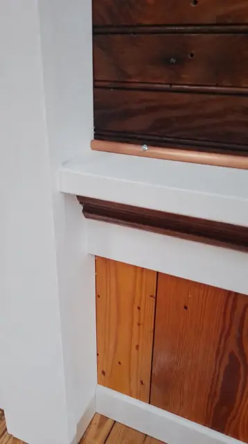 Interior, the white shelf and copper pipe above the paneled wall, with the pine floor and white baseboard below, photo 20 of 32