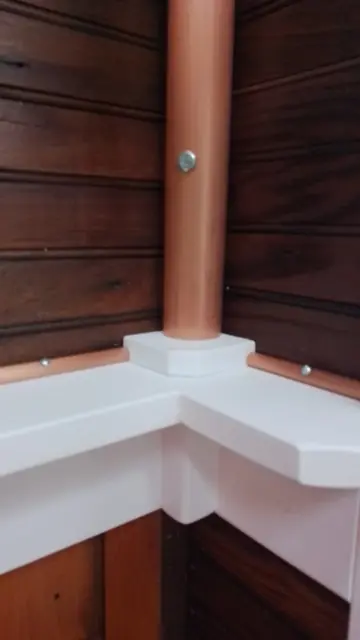 Interior, close-up of the corner shelf where the copper pipe meets the white wooden L-shaped shelf, with copper trim along the paneled walls, photo 25 of 32