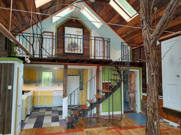Interior, The great room with the loft above, the curved stair, the kitchen and the bathroom door ajar over its wooden threshold, photo 1 of 32