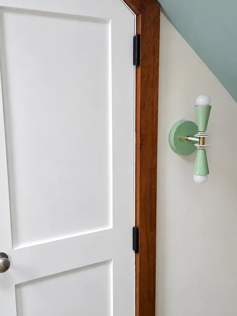 Interior, A white paneled door with black hinges beside a mint-green wall sconce, photo 11 of 32