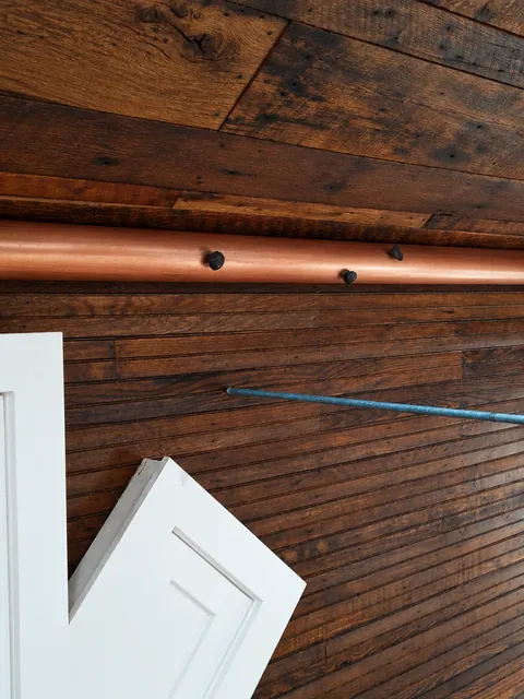 Interior, The copper-clad beam above the paneled wall, with railroad spike heads and a white door below, photo 10 of 32