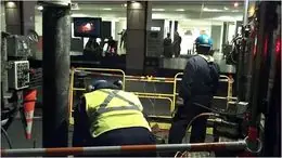 Workers repairing a manhole outside the gallery while a Kephart fire painting plays on a screen inside, as shown in the article