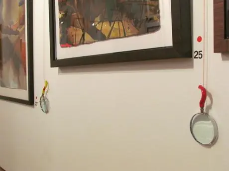 A framed Firepainting with a numbered tag and a magnifying glass hanging beside it