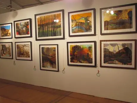 A long wall of framed landscape Firepaintings in the booth