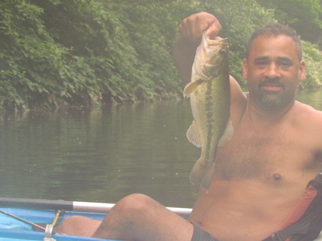 An angler in a kayak holding up a bass on the Potomac.