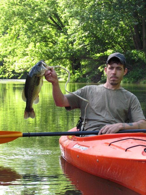 An angler in a kayak holding a bass over the water on the South Branch.